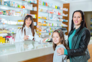 pharmacist and adult woman with her daughter in the drugstore